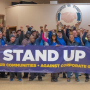 Photo of Volkswagen workers in Chattanooga, TN, holding a large UAW banner that says, "Stand Up."