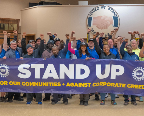 Photo of Volkswagen workers in Chattanooga, TN, holding a large UAW banner that says, "Stand Up."