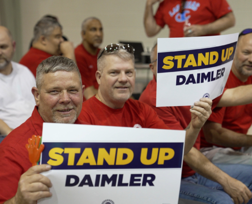 Photo of UAW Daimler members holding "Stand Up Daimler" UAW signs.