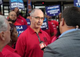 Photo of UAW President Shawn Fain speaking with the media during union rally.
