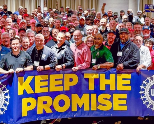 Photo of the UAW Stellantis Bargaining Committee holding a banner that says, "Keep the Promise."
