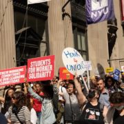 People rallying holding signs reading "students for worker solidarity" and "honk 4 unions"