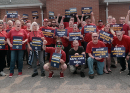 Photo of workers who work at BOSK in Glendale, KY, wearing red shirts and holding UAW signs.