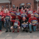 Photo of BOSK workers in Glendale, KY, wearing red shirts and holding UAW signs. Workers at the facility are organizing to form their union, but have faced employer intimidation, retaliation, and coercion.
