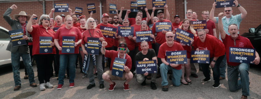 Photo of BOSK workers in Glendale, KY, wearing red shirts and holding UAW signs. Workers at the facility are organizing to form their union, but have faced employer intimidation, retaliation, and coercion.