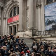 Group of people sitting on sitting on steps in front of building.