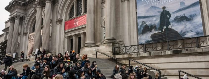 Group of people sitting on sitting on steps in front of building.
