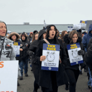 UAW member picketing in winter attire, holding winter coats, protesting.